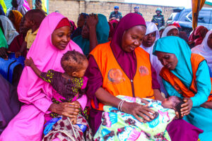 Caregivers and children with health worker at malaria campaign launch in Kaduna, Nigeria