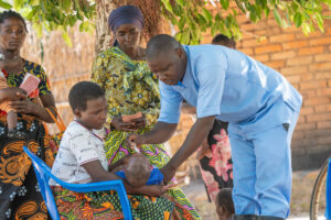 Community health worker providing care to a mother and children during an outreach visit in Malawi.